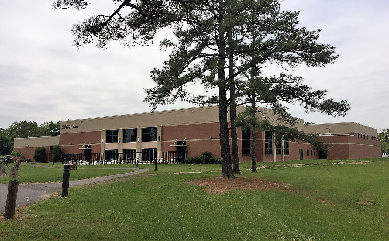 Manassas Park Community Center with brick walls, tall pines, and green lawns.