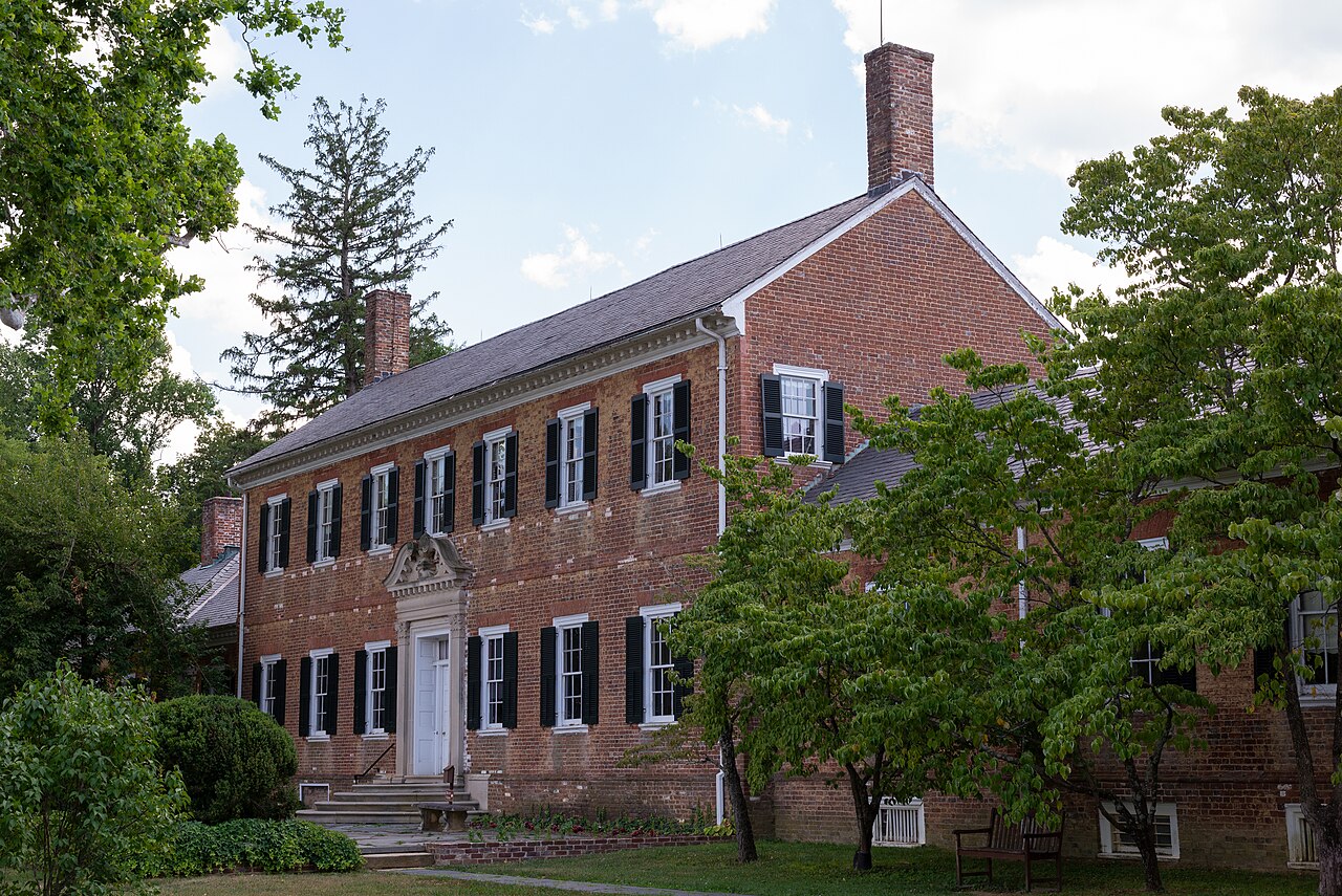 The brick garden facing exterior of Chatham Manor amid green trees in Stafford County, Virginia.